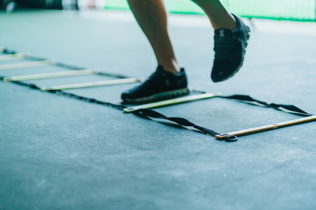 En agility stige og en person i shorts der tager skridt i den