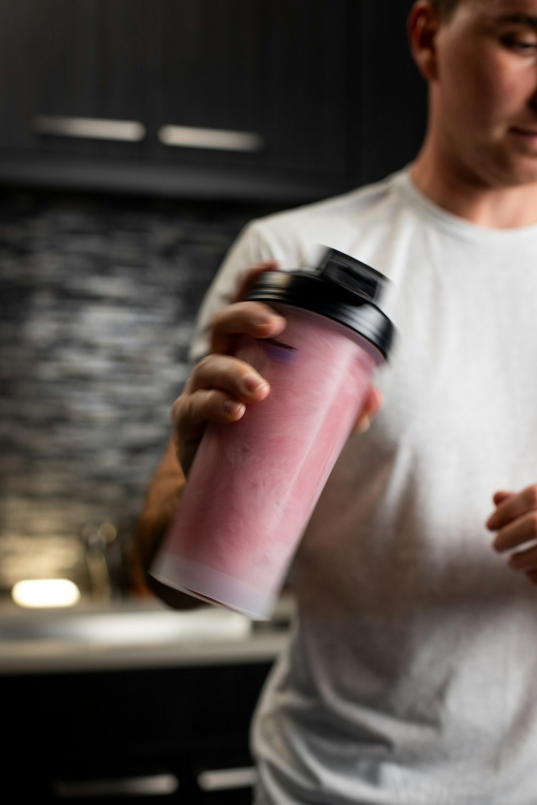En mand ryster en proteinshake med en lyserød farve