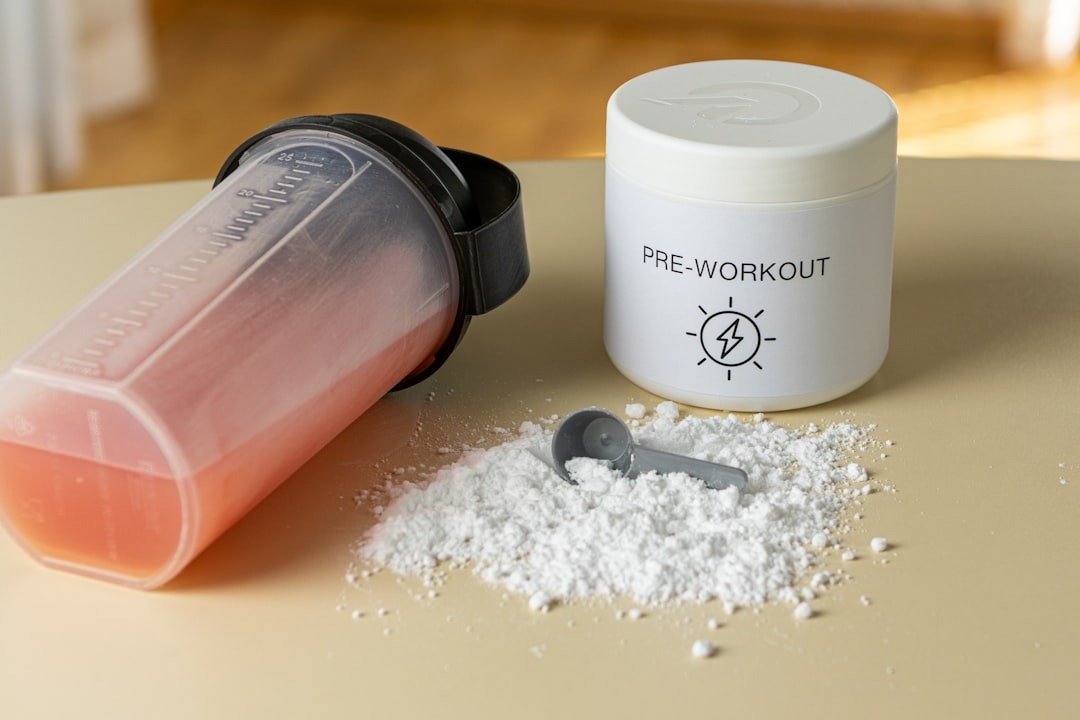 pre workout pulver der ligger på et bord ved siden af en shaker og en kop