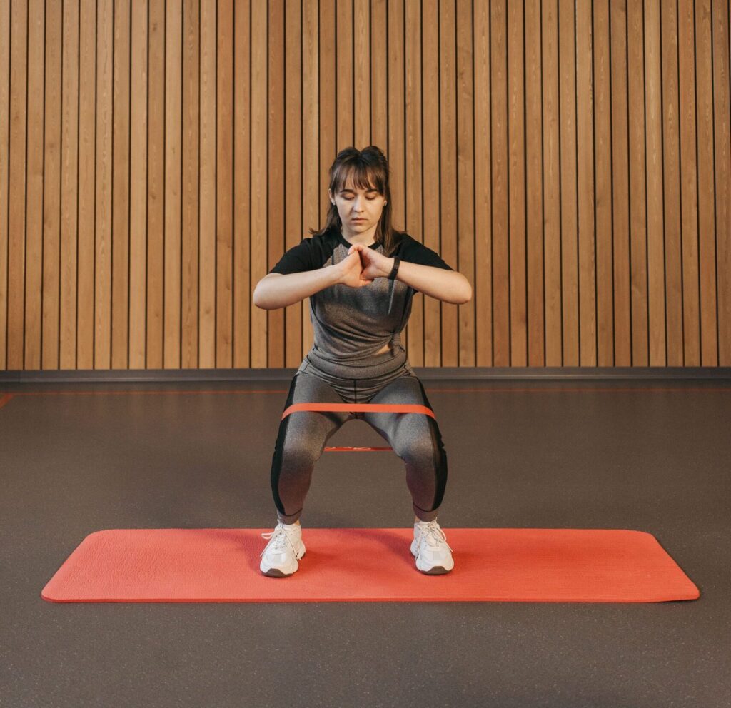 kvinde laver banded lateral walks med en elastik på en yogamåtte