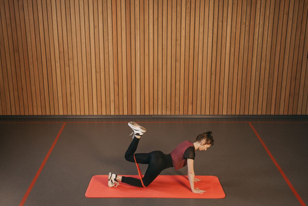 kvinde laver banded leg curls på en yogamåtte